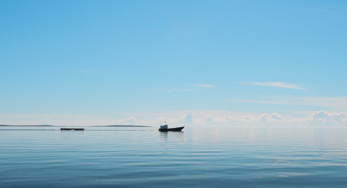 Boat on a very calm ocean under blue sky