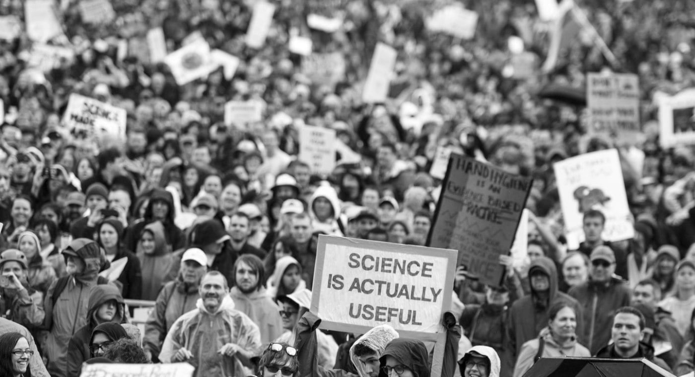 Crowd demonstrating with 'science is actually useful' sign